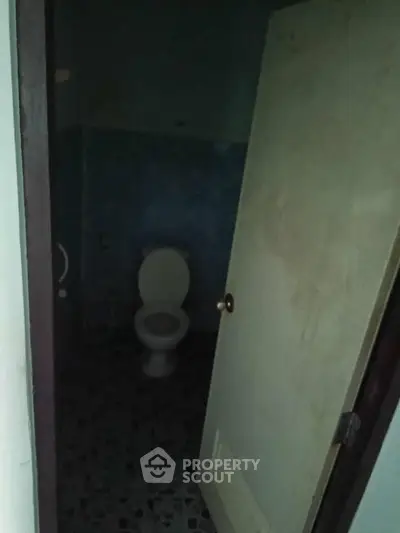 Dimly lit bathroom with closed toilet and tiled floor