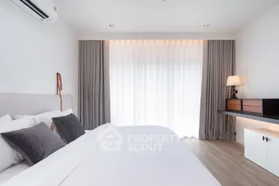 Modern bedroom with elegant decor and natural light through large window.