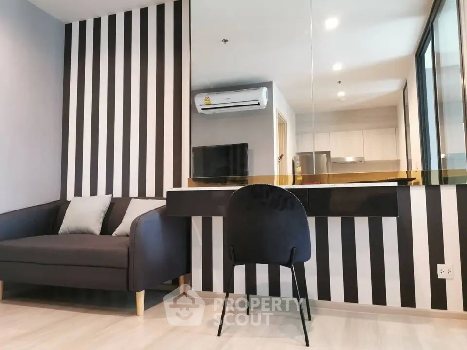 Modern living room with stylish black and white striped wall and sleek furniture.