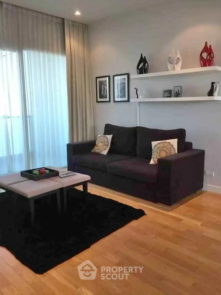 Stylish living room with modern decor and hardwood floors, featuring a cozy sofa and elegant shelving.