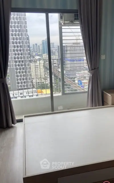 Modern bedroom with large window offering stunning city view in high-rise apartment.