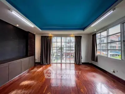Spacious living room with wooden floors and large windows offering ample natural light.