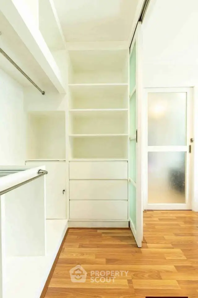 Spacious walk-in closet with wooden flooring and ample shelving in modern apartment.