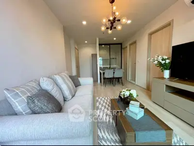 Modern living room with stylish decor and open dining area, featuring elegant lighting and cozy seating.