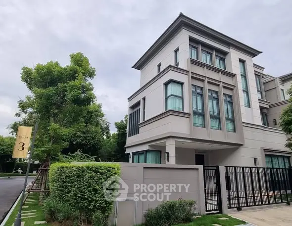 Luxurious modern three-story house with lush greenery and sleek architectural design.