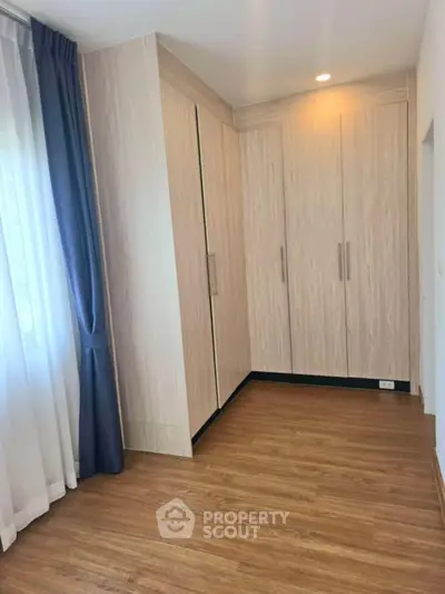 Spacious bedroom with elegant wooden flooring and built-in wardrobe, perfect for modern living.
