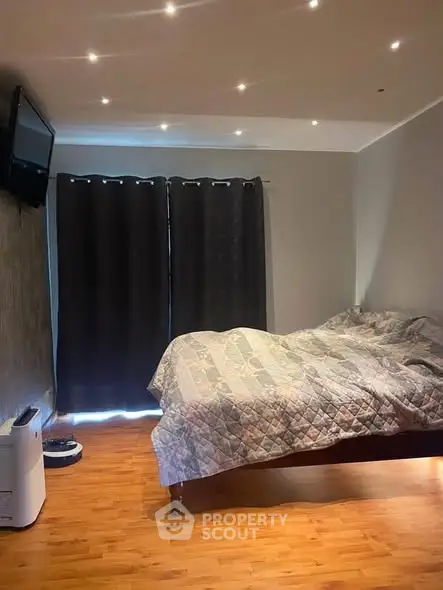 Cozy bedroom with modern lighting and wooden flooring, featuring a comfortable bed and stylish decor.