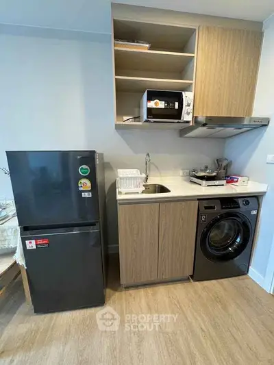 Modern compact kitchen with appliances including fridge, microwave, and washing machine.