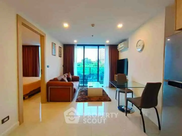 Modern living room with glass doors leading to a balcony, featuring a cozy sofa and dining area.