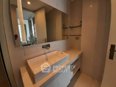 Modern bathroom with sleek sink and large mirror in contemporary apartment.