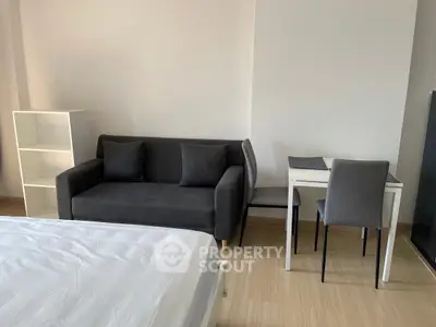 Modern studio apartment with cozy sofa, study desk, and bed in minimalist design.