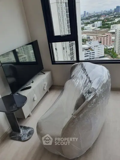 Modern living room with city view, featuring a wrapped sofa and flat-screen TV, ideal for urban living.