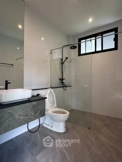 Modern bathroom with sleek design, featuring glass shower enclosure and stylish fixtures.