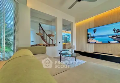 Luxurious living room with modern decor and large TV, featuring elegant staircase and stylish furniture.
