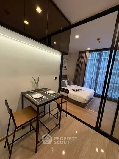 Modern studio apartment with sleek dining area and cozy bedroom, featuring floor-to-ceiling windows.