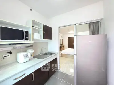 Modern kitchen with sleek appliances and open layout leading to a cozy bedroom.