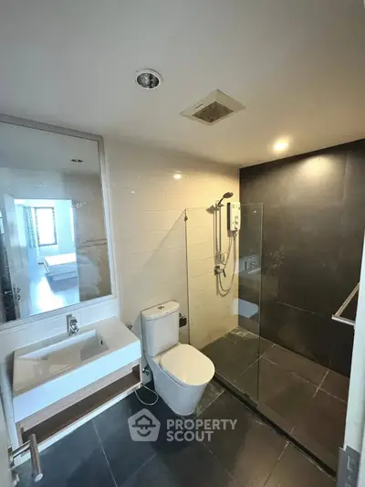 Modern bathroom with sleek design, featuring a glass-enclosed shower and contemporary fixtures.