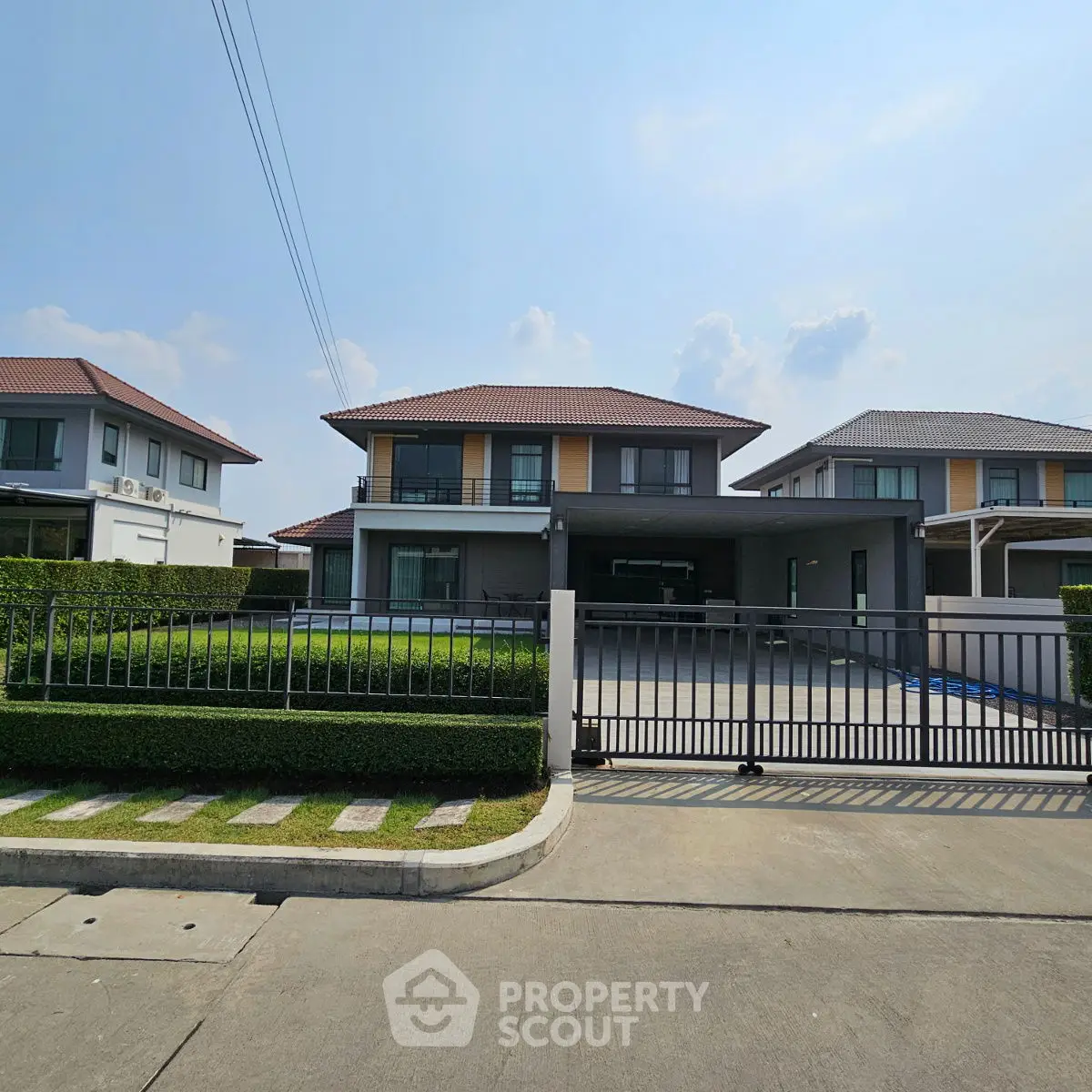 Modern two-story house with gated driveway and manicured lawn in suburban neighborhood.