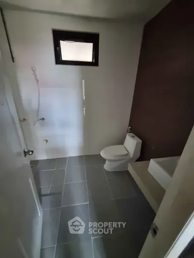 Modern bathroom with sleek design and neutral tones, featuring a toilet and shower area.