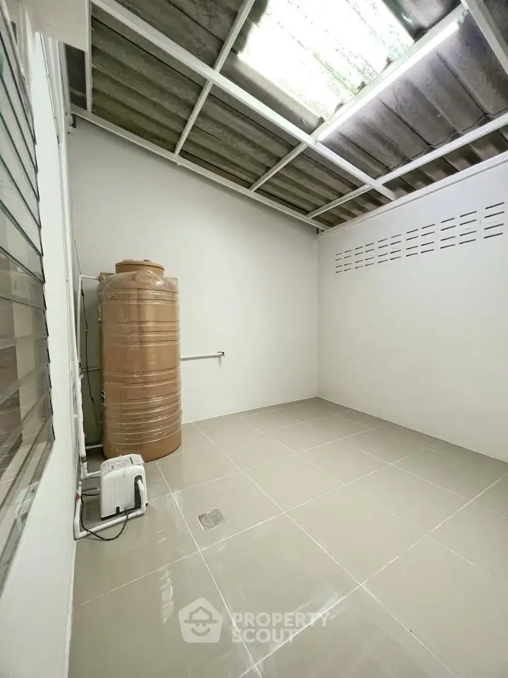 Spacious utility room with water tank and tiled flooring, ideal for storage or laundry setup.