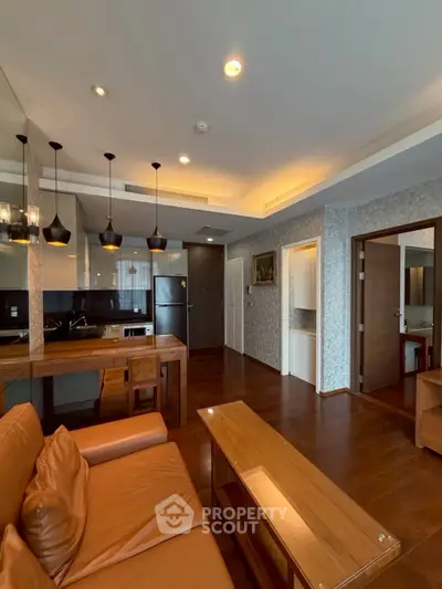 Modern living room with open kitchen, stylish lighting, and wooden flooring in a cozy apartment.
