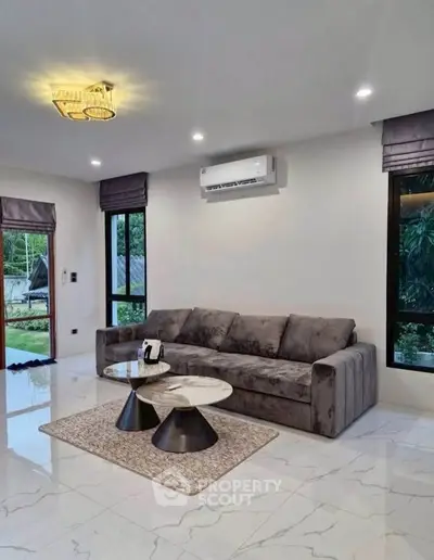 Modern living room with plush gray sofa, stylish coffee tables, and elegant lighting.
