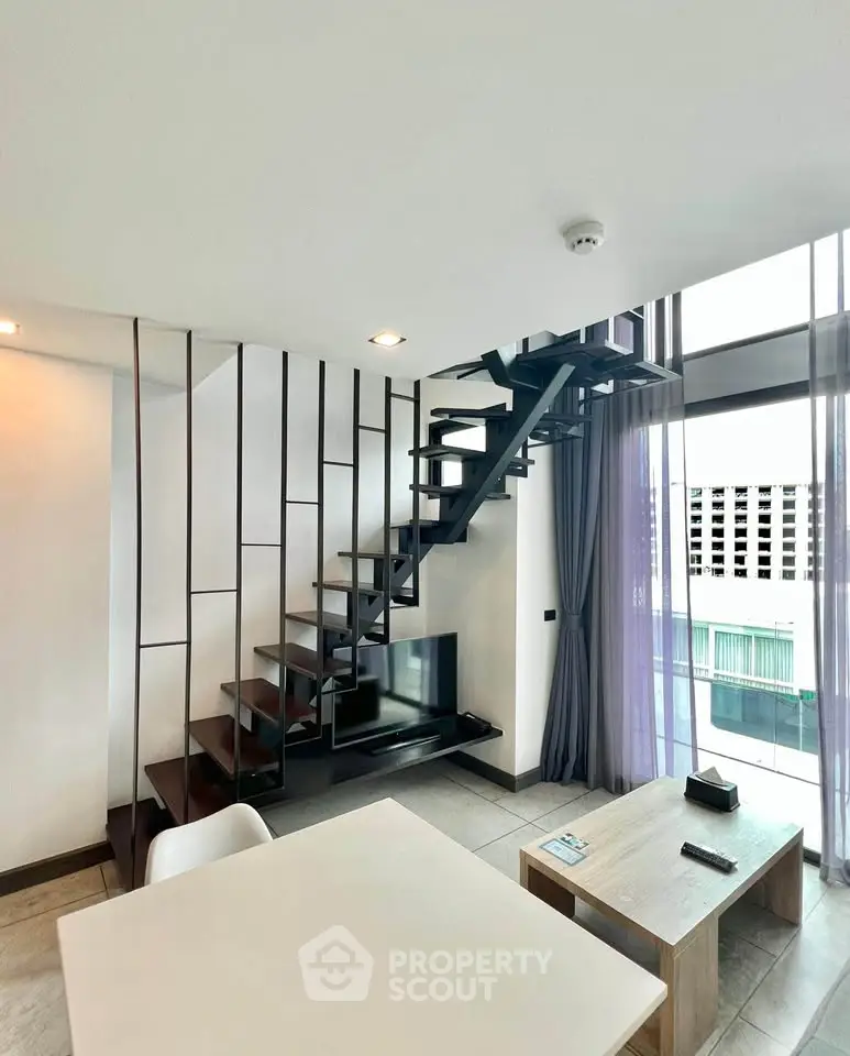 Modern duplex living room with stylish staircase and large windows