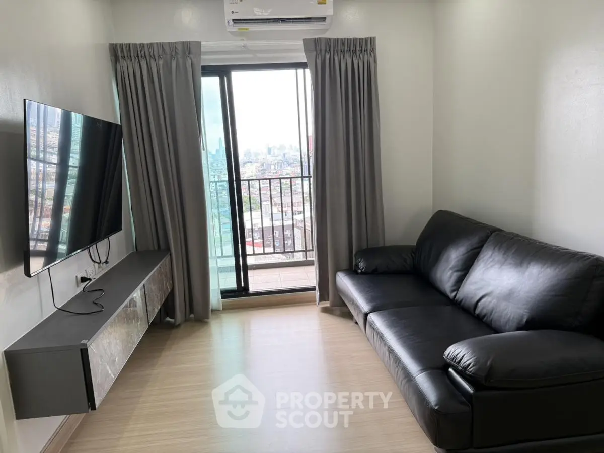 Modern living room with sleek black sofa and wall-mounted TV, offering city views through large window.