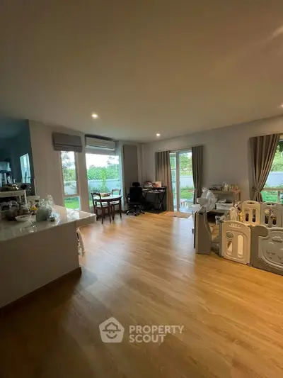 Spacious living room with wooden flooring and garden view, perfect for family gatherings.