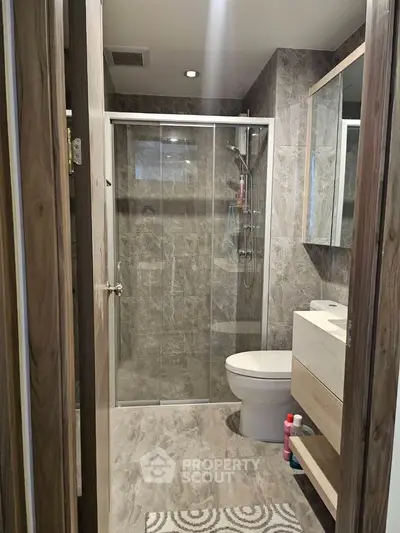 Modern bathroom with glass shower and sleek fixtures in contemporary apartment.