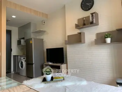 Modern studio apartment with sleek kitchen and cozy living area, featuring stylish shelving and contemporary decor.