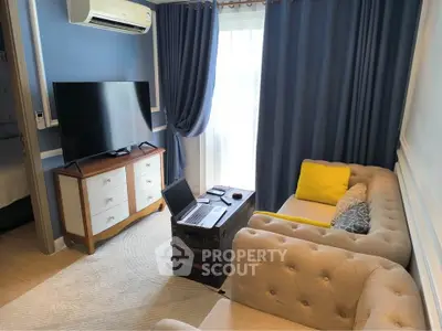 Charming living room with plush sofa, modern TV, and elegant blue curtains.