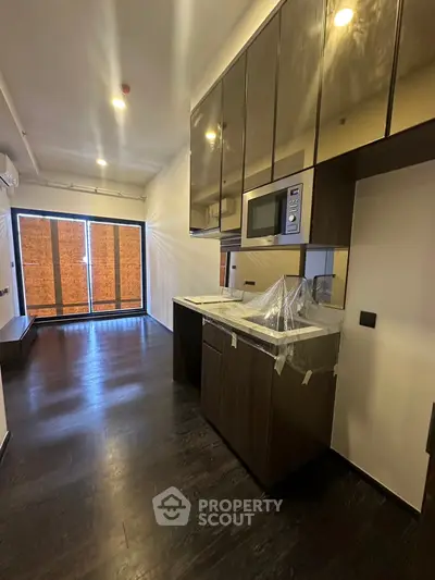Modern kitchen with sleek cabinetry and built-in microwave in a stylish apartment.