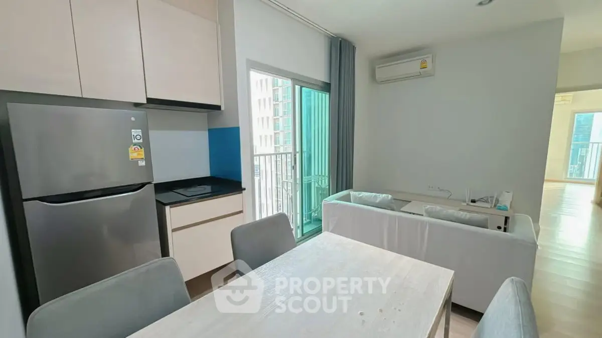 Modern apartment interior with open kitchen and cozy living area, featuring a balcony view.