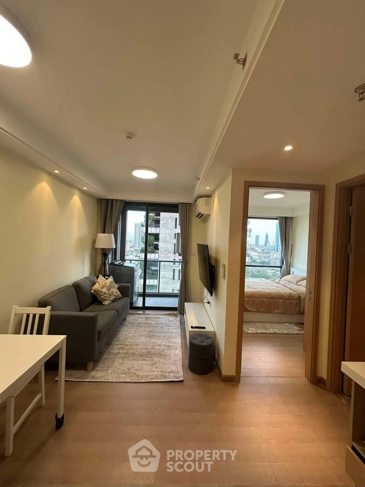 Modern apartment interior with cozy living room and bedroom, featuring a balcony with city view.