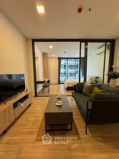 Modern open-plan living room with stylish furniture and view into a cozy bedroom, perfect for urban living.