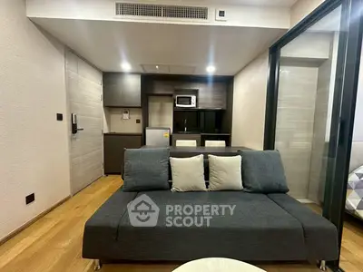 Modern living room with sleek furniture and compact kitchen in open layout apartment.