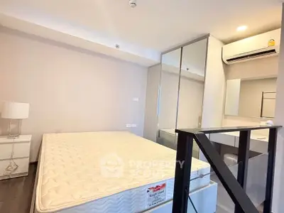 Modern bedroom with minimalist design, featuring a large bed, mirrored wardrobe, and air conditioning unit.