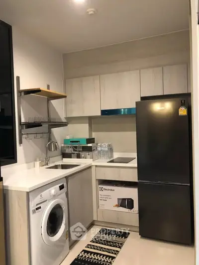 Modern compact kitchen with washing machine and fridge in sleek apartment