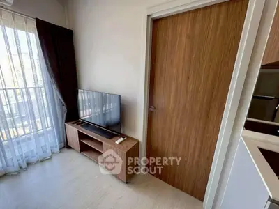 Modern living room with sleek TV stand and large window with sheer curtains
