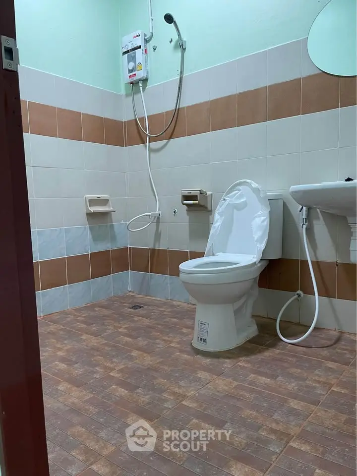 Modern bathroom with tiled walls and floor, featuring a toilet and shower setup.