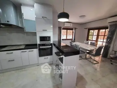 Modern open kitchen with sleek design and dining area, featuring contemporary appliances and stylish lighting.
