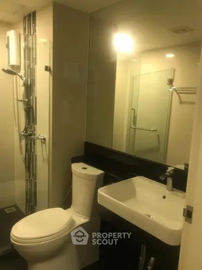 Modern bathroom with sleek fixtures and glass shower enclosure.