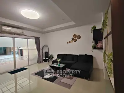 Spacious modern living room with sleek black sofa and stylish decor, perfect for relaxation and entertainment.