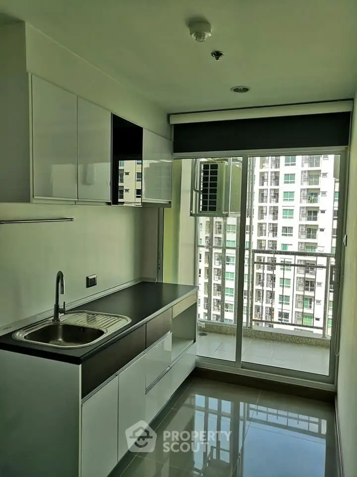 Modern kitchen with sleek cabinetry and balcony view in high-rise apartment