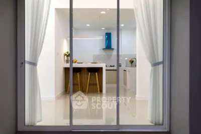 Modern kitchen with sleek design and open layout viewed through glass doors.