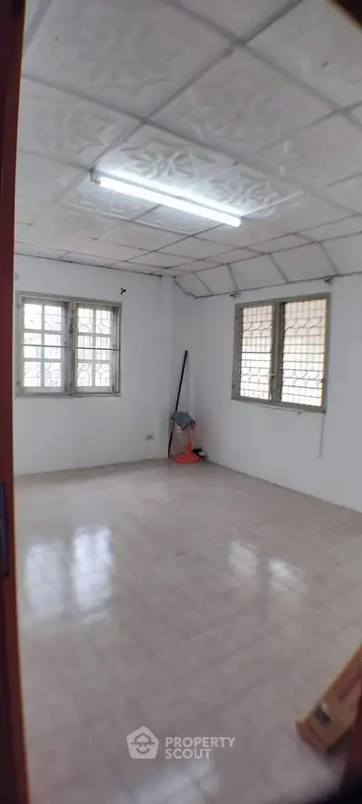 Spacious room with tiled floor and large windows, ideal for versatile use.