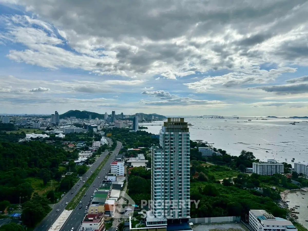 Stunning aerial view of coastal cityscape with modern high-rise building and expansive ocean horizon.