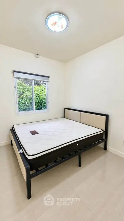 Spacious bedroom with natural light and garden view, featuring a comfortable bed and minimalist decor.