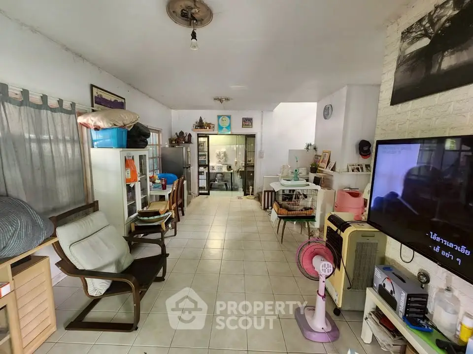 Spacious living room with tiled floor and eclectic decor, featuring comfortable seating and a large TV.